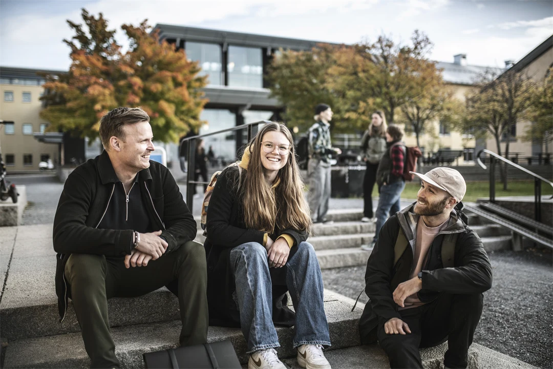 Tre studenter som sitter i en trappa utanför Campus Östersund
