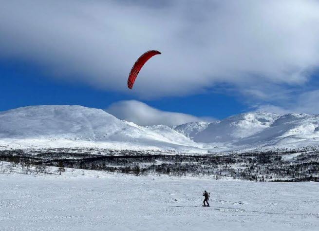 Person som utövar kiting på skidor i fjällmiljö.