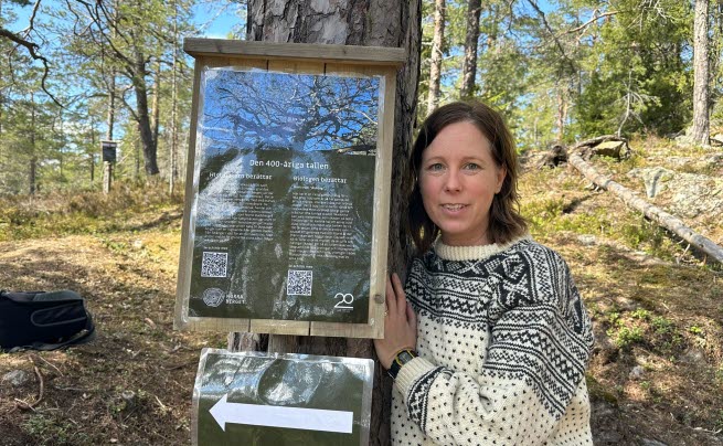 Forskaren Jennie Sandström står bredvid ett träd. 