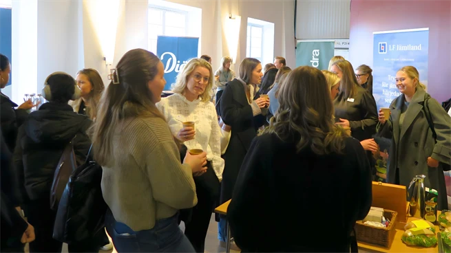 Studenter och företagsrepresentanter minglar över ett bord med smörgåsar