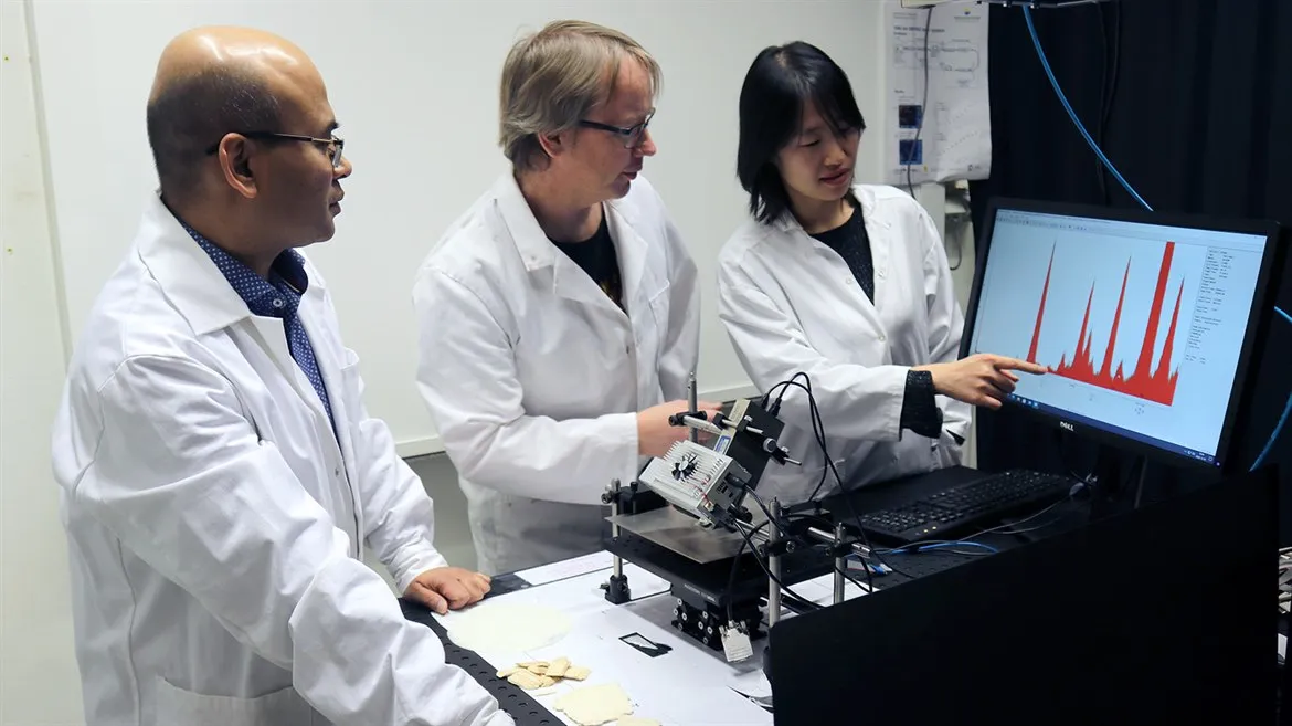 Tre forskare diskuterar resultat i ett labb.