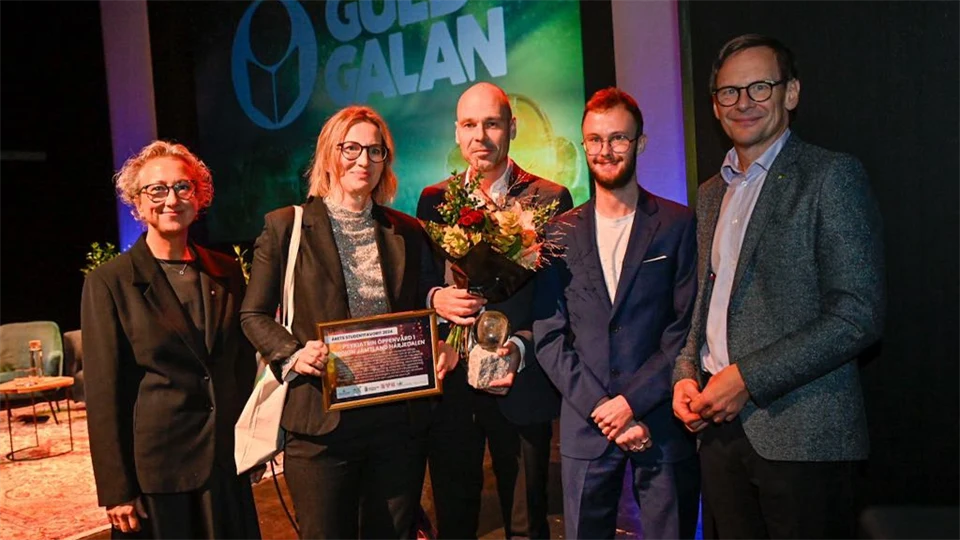 Tre män och två kvinnor med diplom och blommor i samband med prisutdelning
