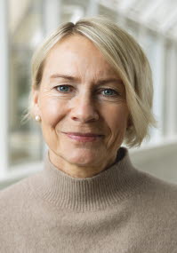 En kvinna med blont hår i pagefrisyr och beige tröja i halvpolomodel.