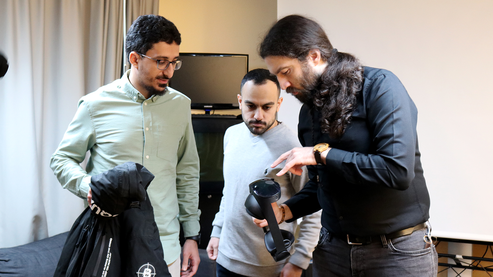 Three men looking at a VR headset