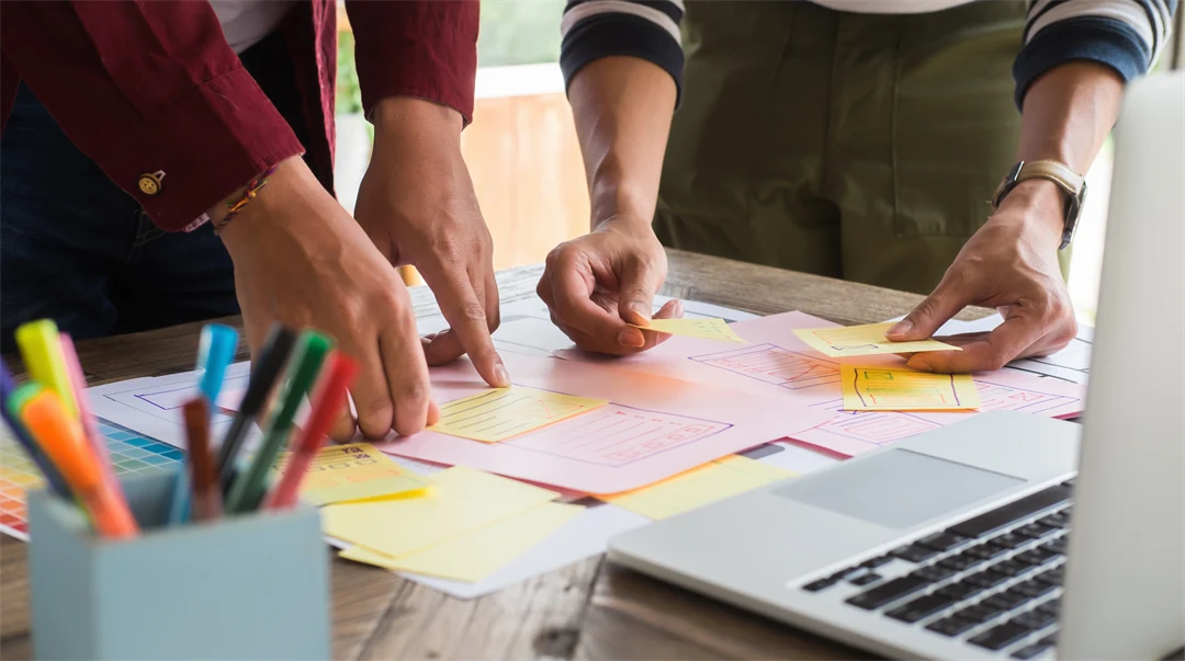 Händer som flyttar post-it lappar på ett bord.