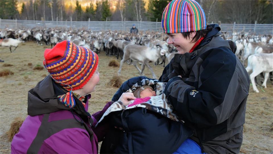 Kvinna med två barn i ett rengärde.