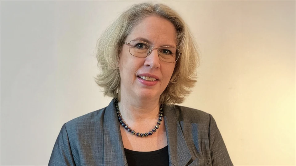 Kvinna med glasögon i grå kostym och halsband