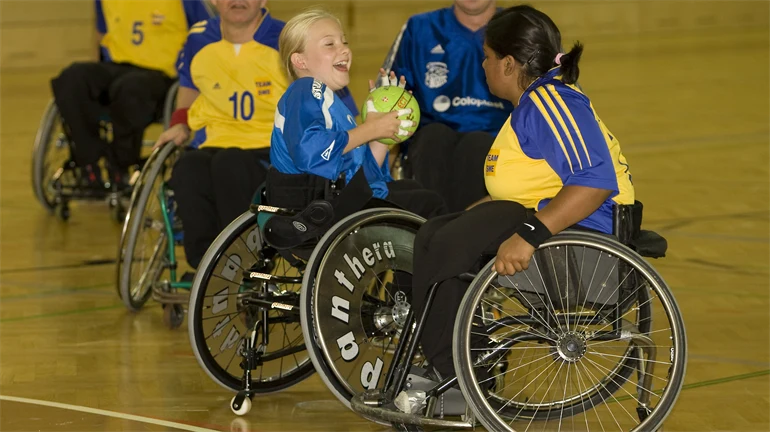 handboll parasport, 5 människor med nummerlappar  i rullstol i sporthall