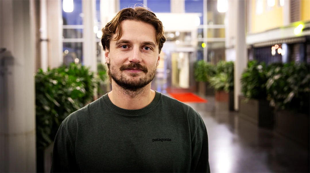 Man i grön tröja står i en ljushall.