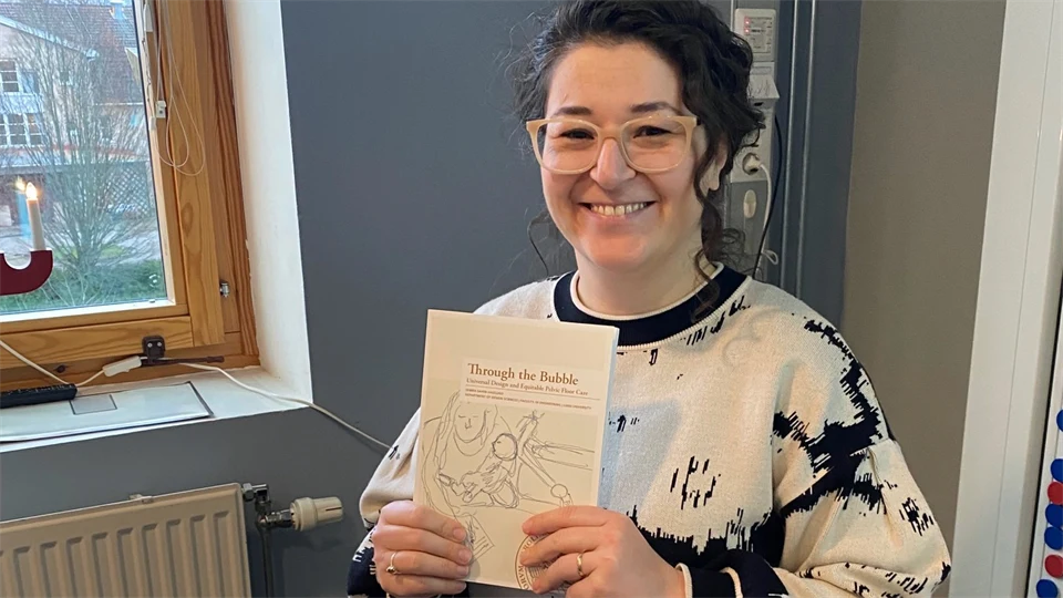 en kvinna ler och håller i ett häfte