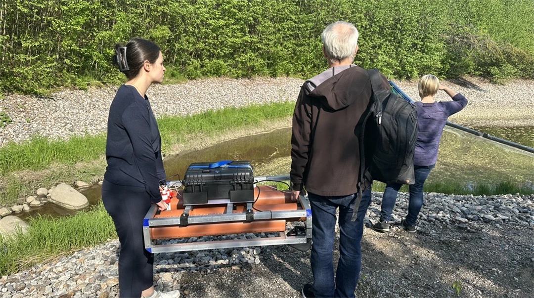 Två personer bär en liten orange båt som möter sedimentnivåer