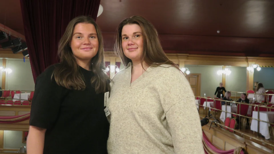 Elin Sveningson och Felicia Persson står bredvid varandra på läktaren inne i lokalerna för Turismdagen 