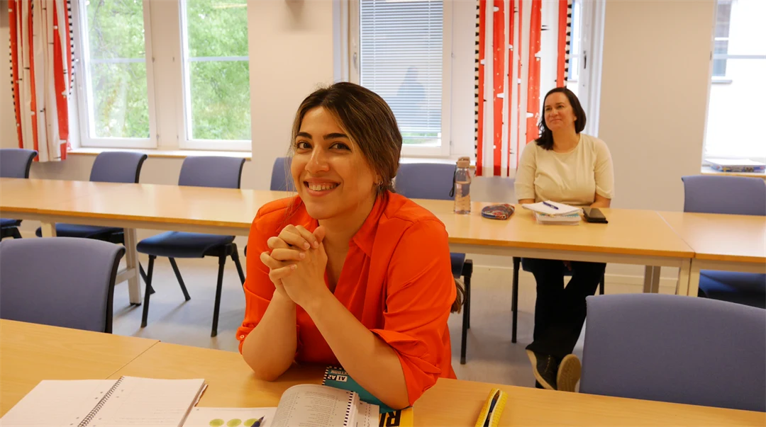 Två kvinnor sitter i en föreläsningssal med böcker framför sig.