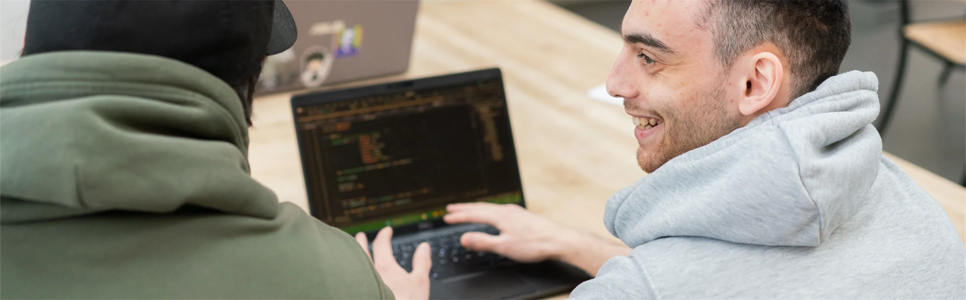 En man sitter vid en laptop och ler. 