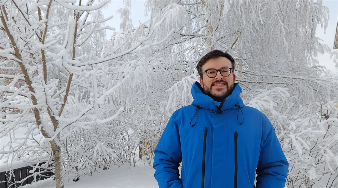 A man with a blue jacket stand in a snowy landscape