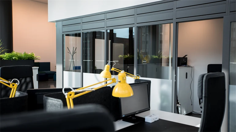 Open office space with black chairs, yellow desk lamps and light walls.