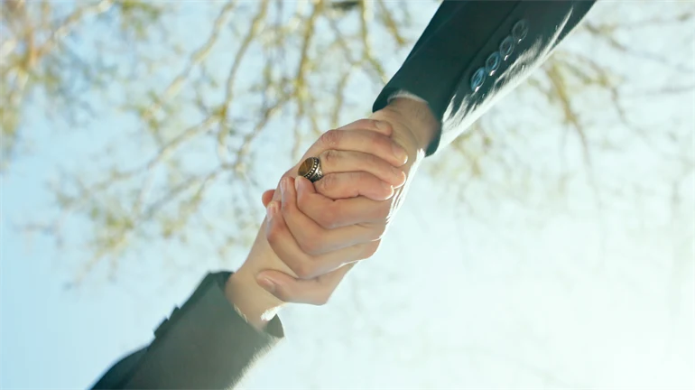 Två händer som håller i varandra utomhus