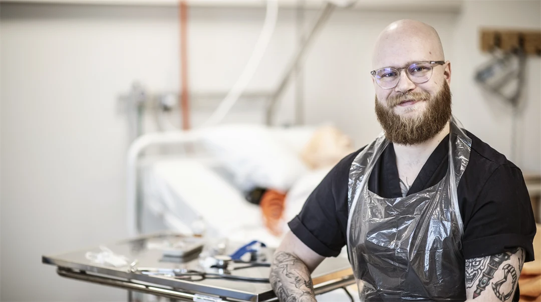 En man med skägg är i en sjukhusmiljö.