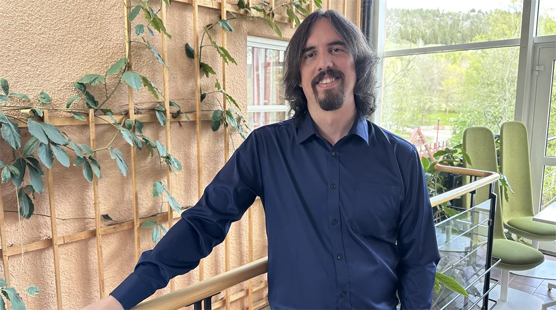 En man med blå skjorta och långt brunt hår