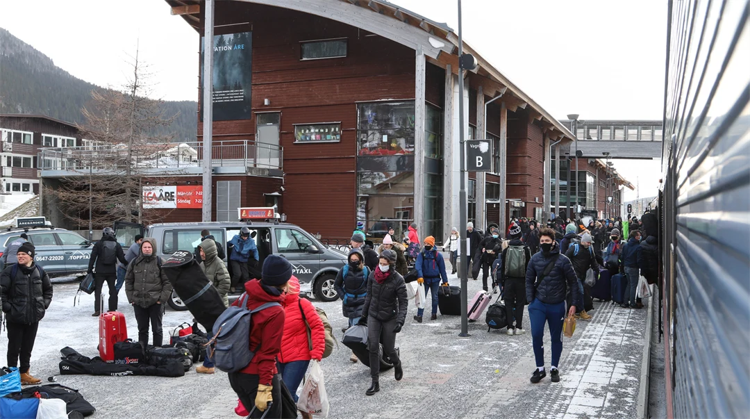 Turister utanför Åre Station, det är vinter och lite snö ligger kvar på marken.