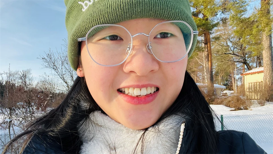  A woman in a winter landscape with trees and snow in the background.