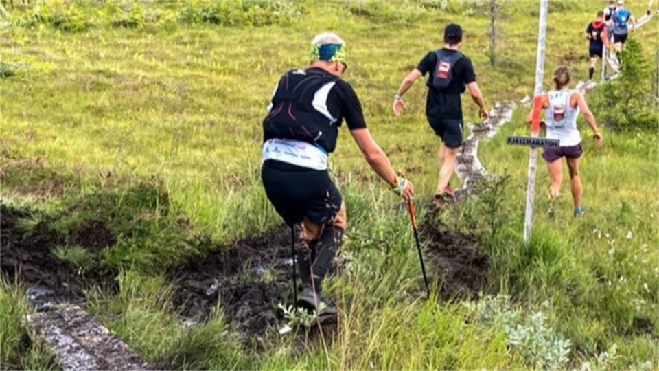 Människor som springer utomhus längs en lerig led i fjällmiljö 