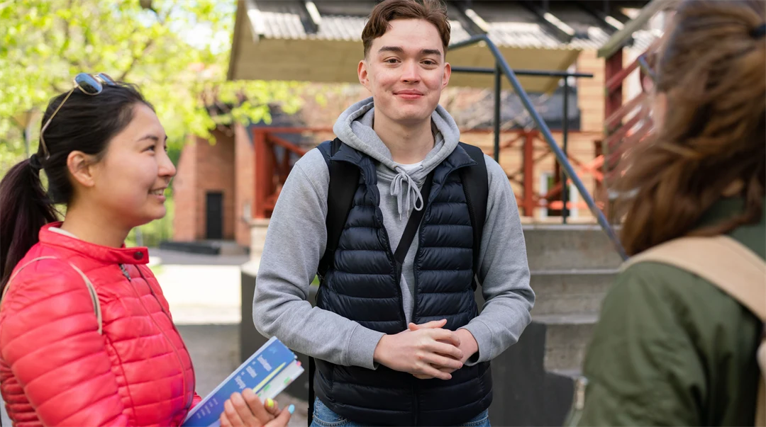  En grupp studenter som står och pratar med varandra utanför campus. 