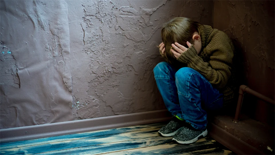 Pojke sitter uppkrupen i hörnet av ett rum