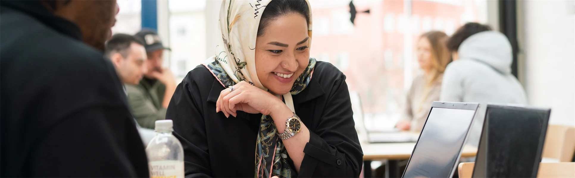 A women sitting at a laptop and smiles. 