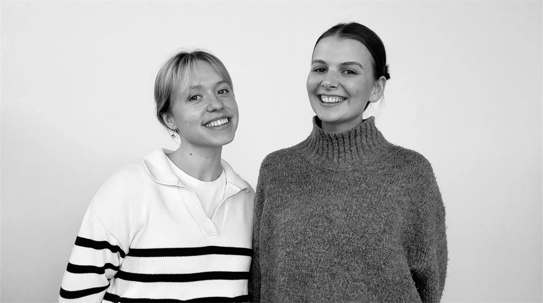 Svartvit bild med två kvinnor mot grå bakgrund.