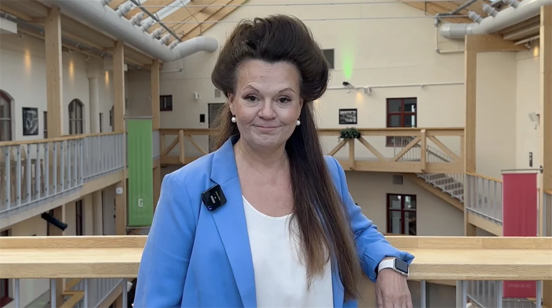 Kvinna i blå kavaj och mörkbrunt hår 