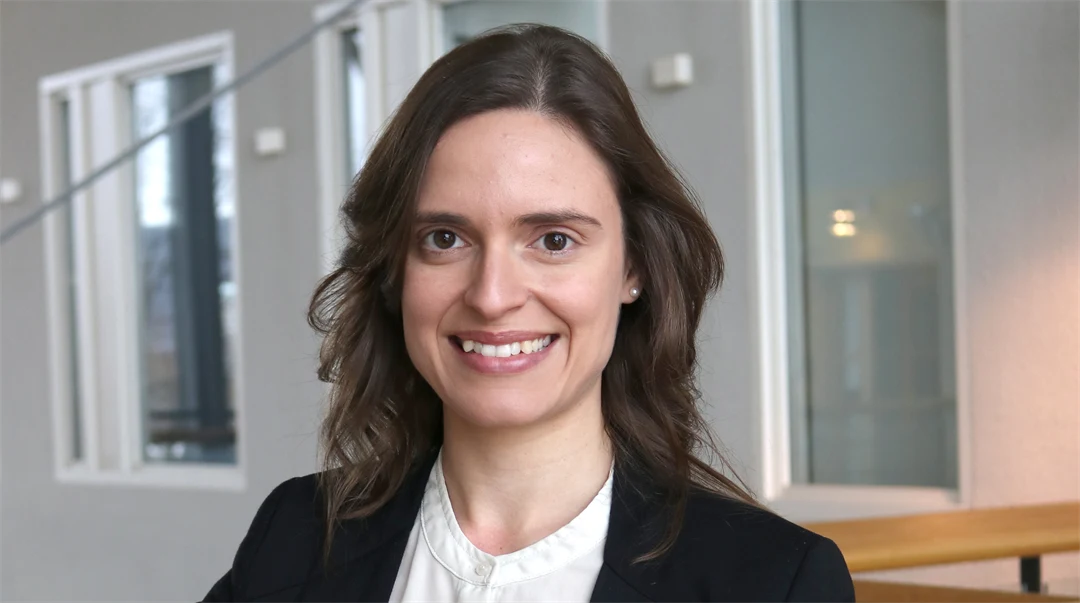 A woman looks into the camera and smiles.