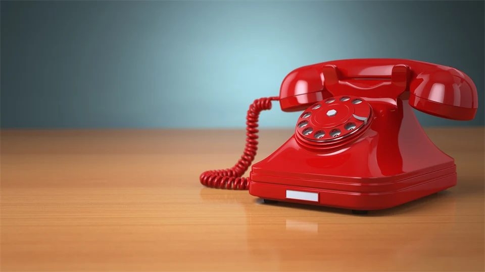 Röd gammal telefon på ett skrivbord.
