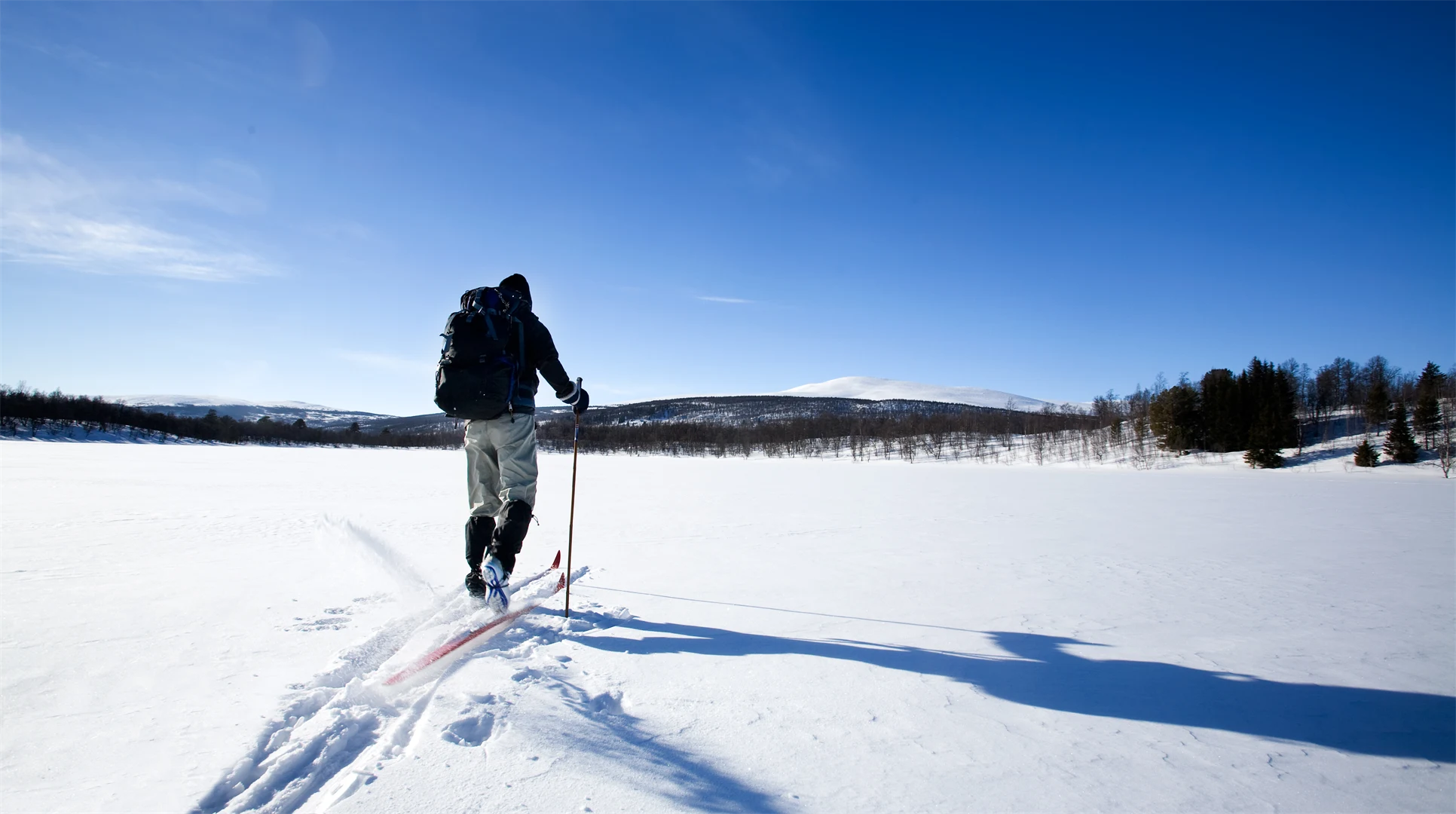 man med ryggsäck åker skidor på sjö
