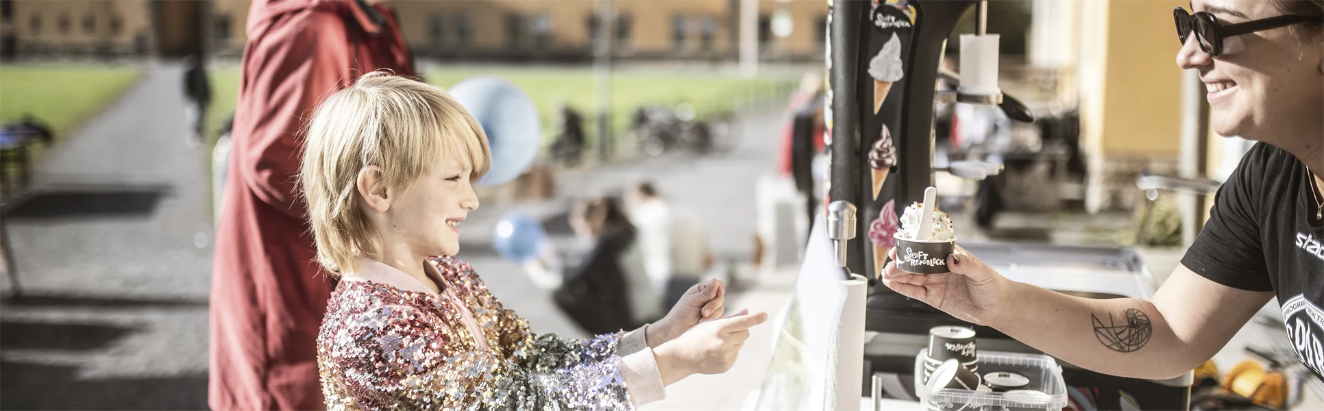 En liten pojke tar emot en mjukglass.