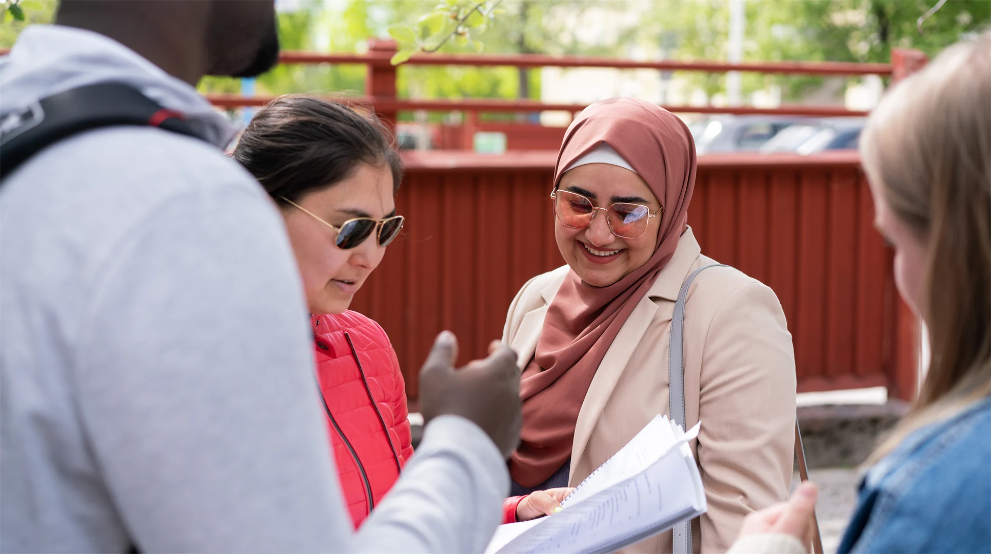 En grupp studenter som står och pratar med varandra utanför campus. 
