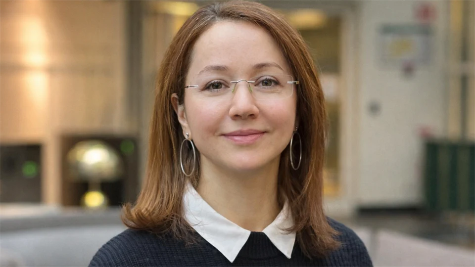 A woman looks into the camera and smiles.