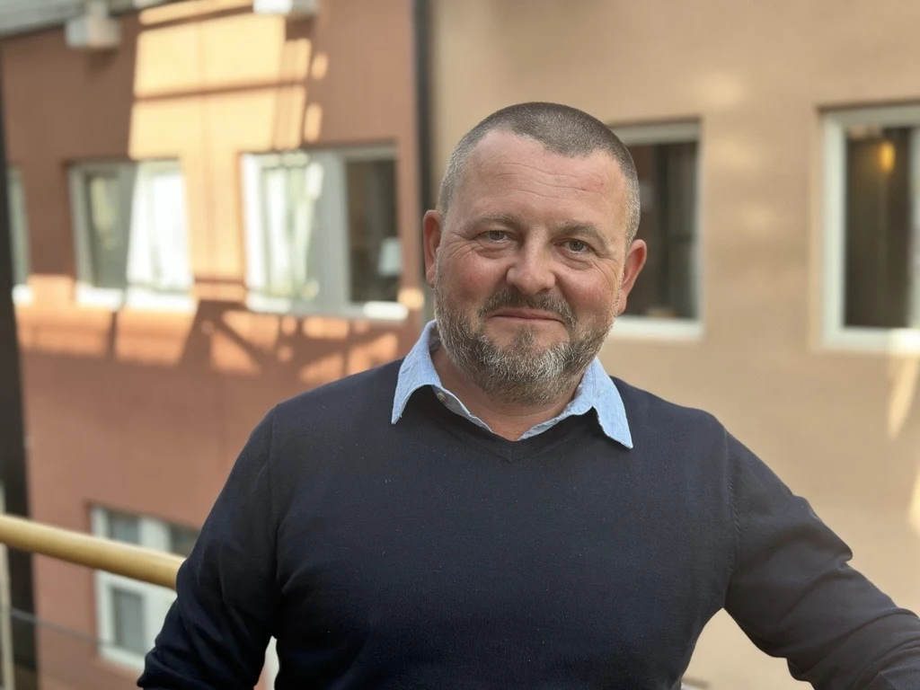 En man med snaggat mörkt hår och en mörkblå tröja