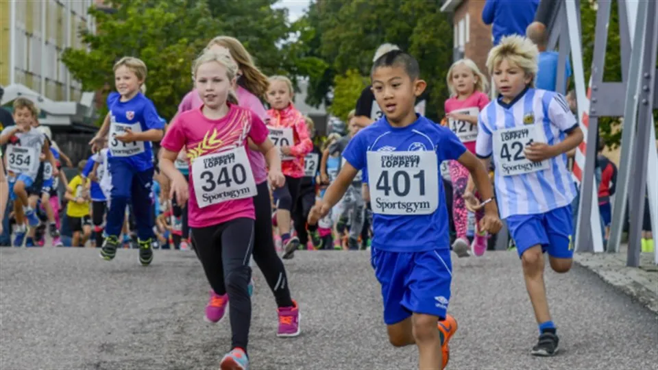 barn med nummerlappar springer i stadsmiljö