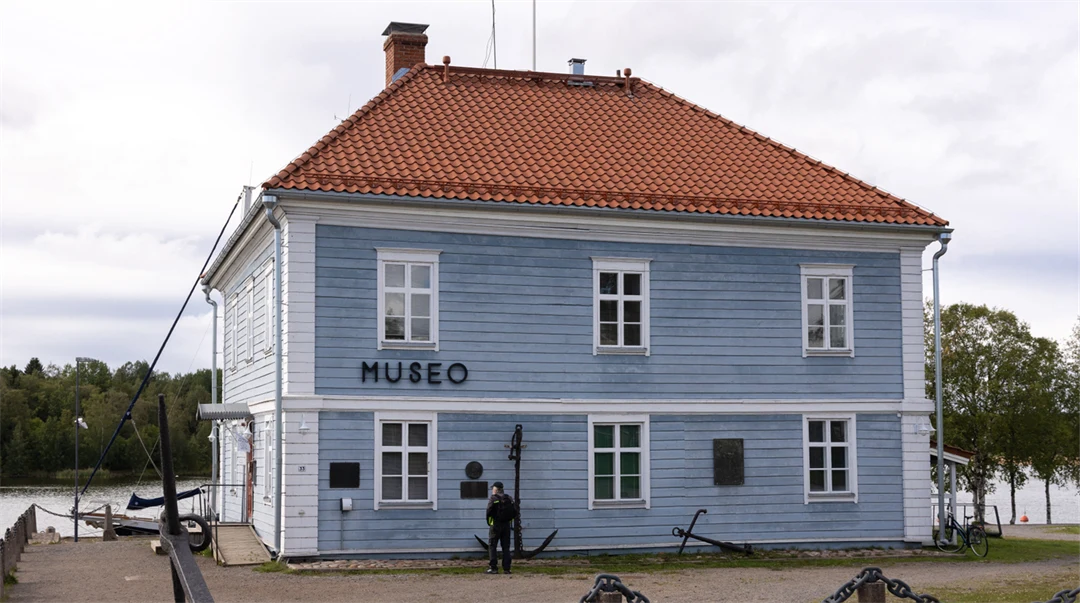 Ljust blått trähus med vita knutar och tegeltak. På fasaden står Museo. 