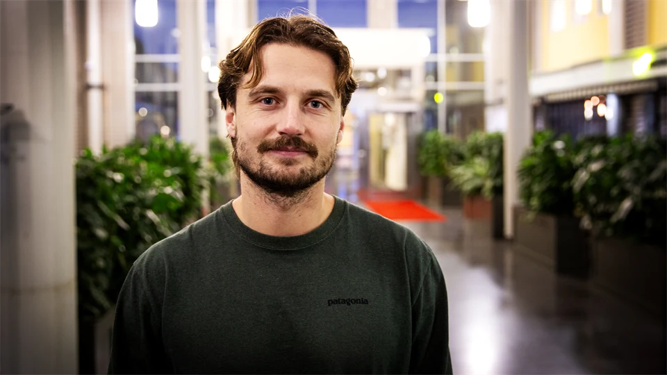 Man i grön tröja står i en ljushall.