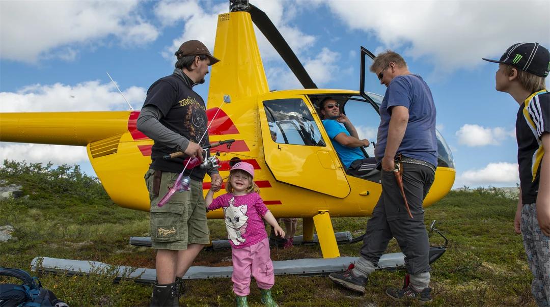 Två män och två barn intill en gul helikopter.
