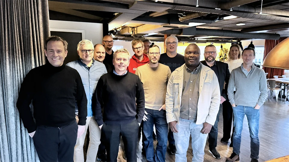 En grupp på 12 personer står mot kameran och ler