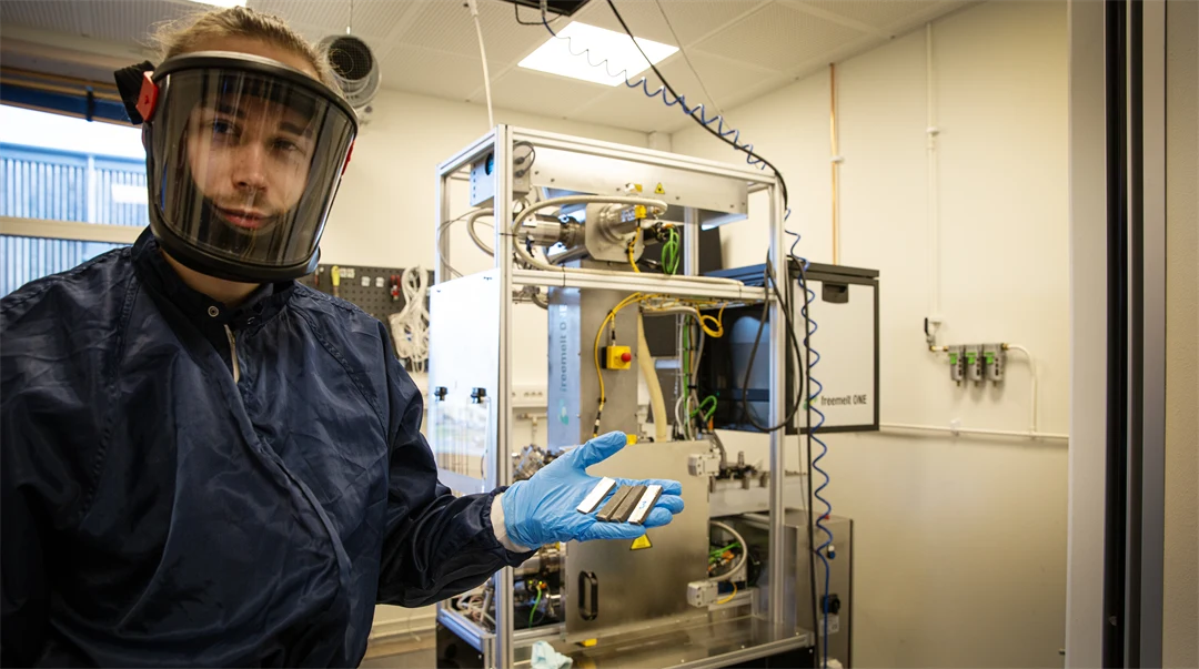Man står iklädd skyddsdräkt och friskluftsmask och håller i tungstenar.