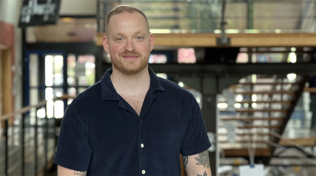 En man med mörk tshirt och tatueringar står i ett trapphus