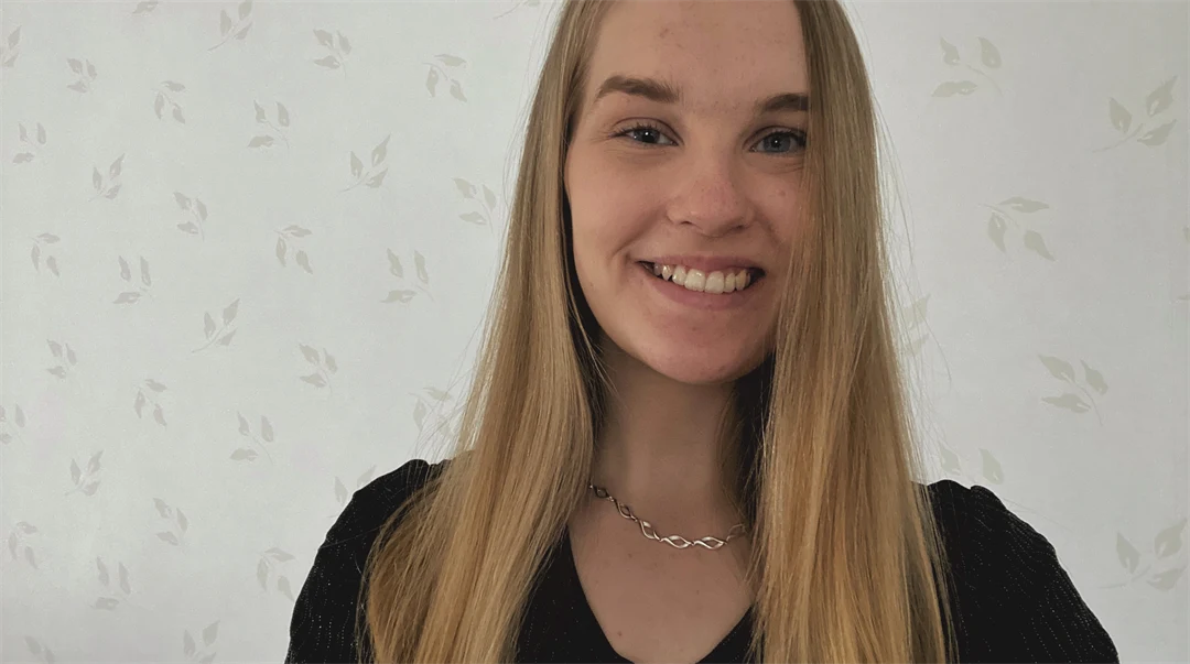 Ljushårig kvinna framför en ljus men mönstrad tapet