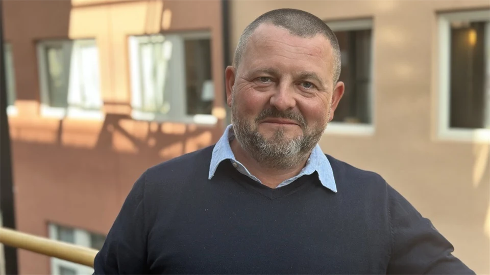 En man med snaggat mörkt hår och en mörkblå tröja