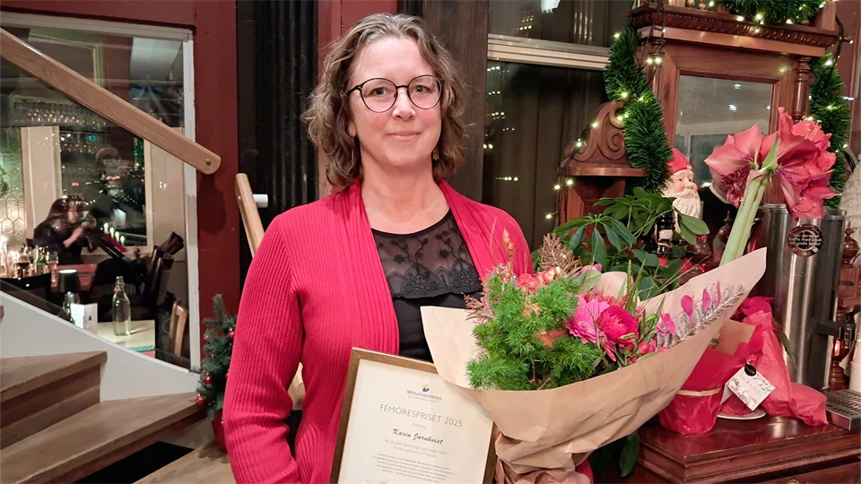 Kvinna i röd kavaj med diplom och blombukett i famnen