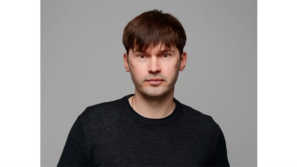 A man with dark, short hair, wearing a black shirt.