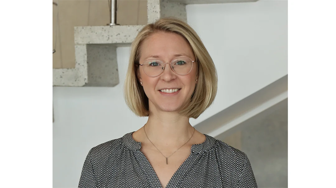 A fair-haired woman with glasses and a gray blouse.